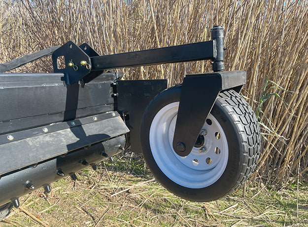 Power rake drum and gauge wheel seen from behind the machine