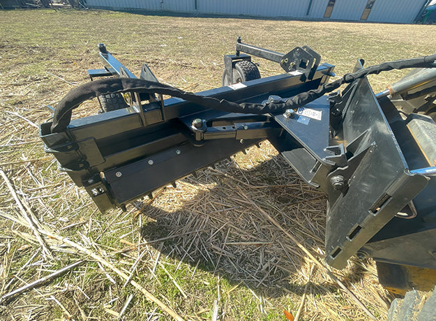 Power rake seen from behind at ground level, gauge wheel and drum housing in frame