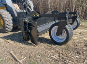 Power rake on a skid steer working cut ground, the removable side plate and gauge wheel in view