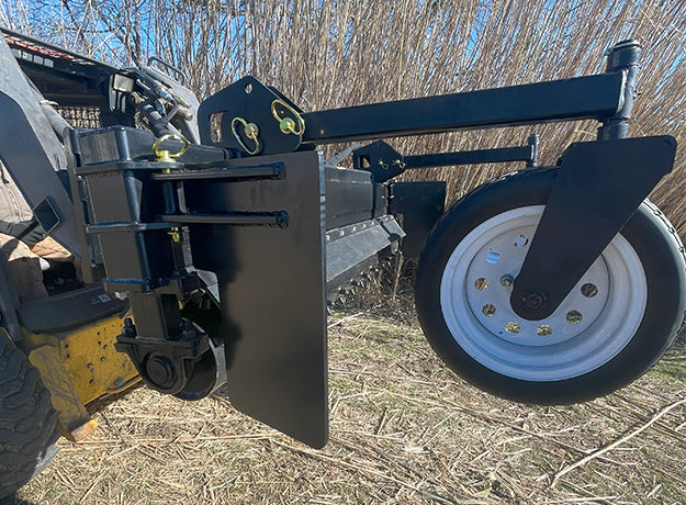 Close-up of a power rake gauge wheel on its swing arm beside the removable side plate