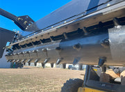 Looking along the power rake drum from the end, carbide teeth in a spiral row against the sky