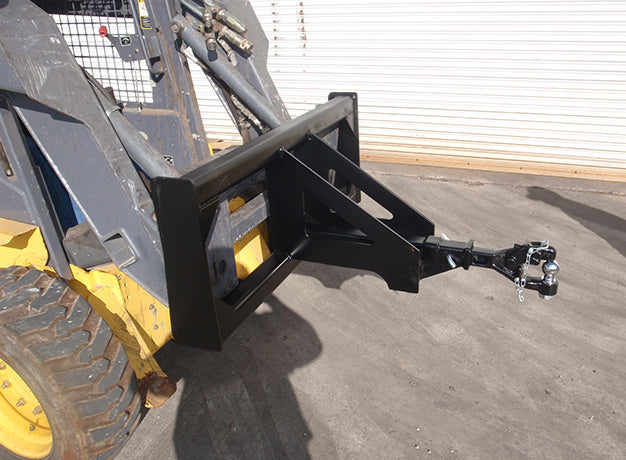 Trailer spotter on a skid steer at ground level, showing the frame's flat foot resting upright on the pad