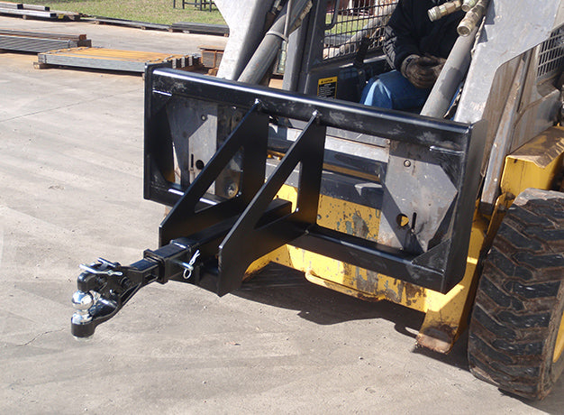 Operator seated in a skid steer with the trailer spotter mounted and the hitch ball facing outward
