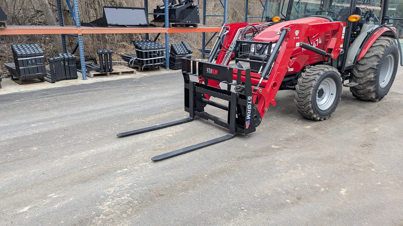 Storm 2000 pallet forks mounted on a red compact tractor loader on gravel