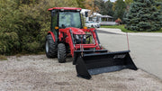 Storm angle snow blade mounted on a red compact tractor, side view with the blade angled to the right