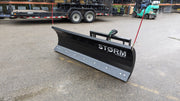 Storm angle snow blade on pavement by a trailer, side view showing the cutting edge and moldboard