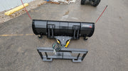 Storm angle snow blade laid out on pavement beside its mount frame, showing the moldboard and the hose set