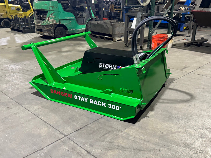Storm 60 inch brush cutter finished in green, three-quarter view on a shop floor with hoses coiled over the motor housing