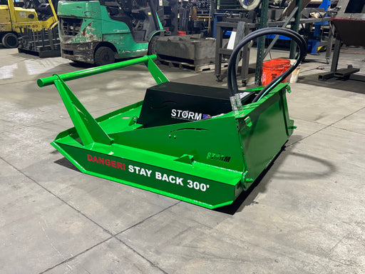 Storm 60 inch brush cutter finished in green, three-quarter view on a shop floor with hoses coiled over the motor housing