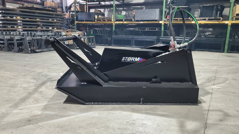 Storm 60 inch brush cutter from the side in a warehouse, showing the deck skirt, brush guard, and hose routing