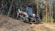 Storm HD root and brush grapple mounted on a white compact track loader at the edge of a cleared wood line
