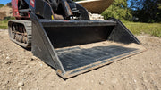 Storm mini bucket on a Toro Dingo track loader outdoors, angled view across the open bucket mouth