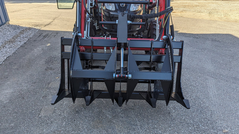 Storm rake and brush grapple on a red tractor loader, head-on view across the full width of the serrated tines