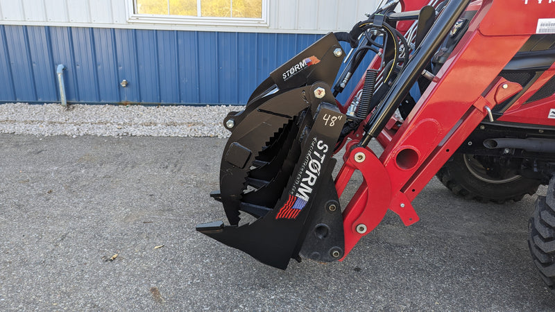 Storm 48 inch rake and brush grapple on a red tractor loader, angled view of the tines and the grapple arm