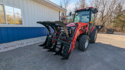 Storm 48 inch rake and brush grapple on a red tractor beside a building, head-on view across the tine bar
