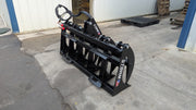 Storm rake and brush grapple set on pavement beside a building, three-quarter view of the tine bank