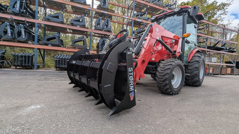 Storm 60 inch two cylinder rake and brush grapple on a red tractor loader, three-quarter view of the arms over the tines