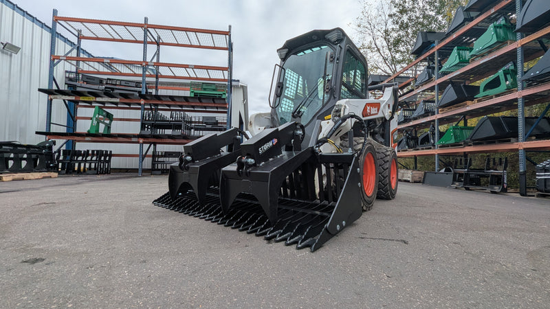 Storm rock and brush grapple on a Bobcat skid steer, three-quarter view of the tine bar and the twin arms