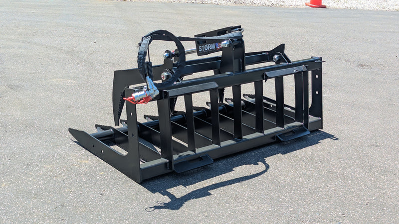 Storm single cylinder root and brush grapple on pavement, angled view of the tine bar and the single arm cylinder