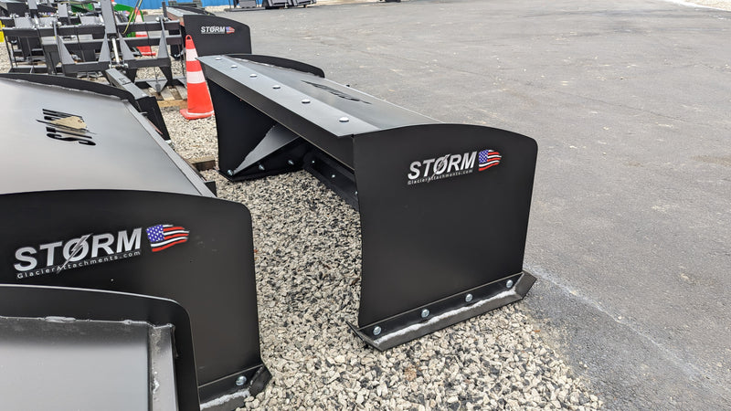 Storm box snow pusher on gravel beside a building, angled view of the side plates and mount
