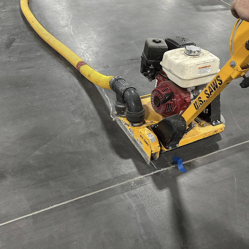 Operator pulling the CC-100 backward along a floor crack with vacuum hose