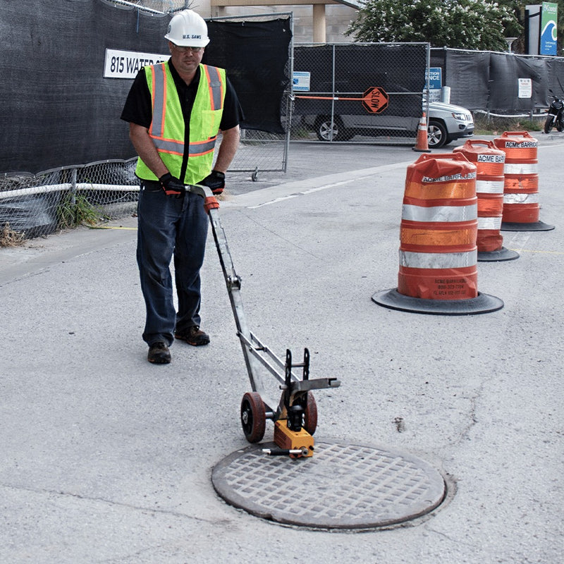 Operator lifting a cover with the aluminum dolly at a manhole