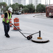 Aluminum dolly tilted back carrying a lifted manhole cover