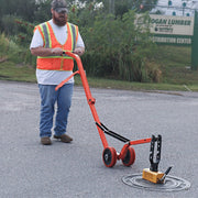 Curved steel dolly carrying a lifted cover across pavement