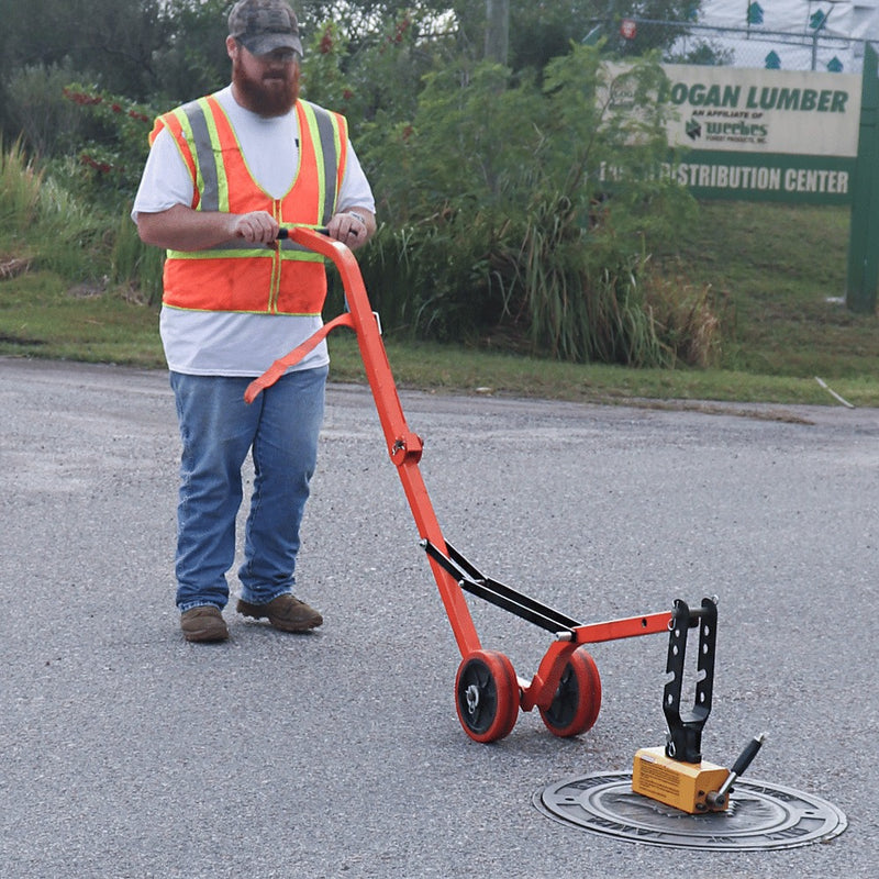 Curved steel dolly carrying a lifted cover across pavement