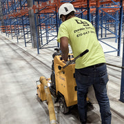 Operator guiding the MC-1000 along a warehouse floor joint between pallet racks
