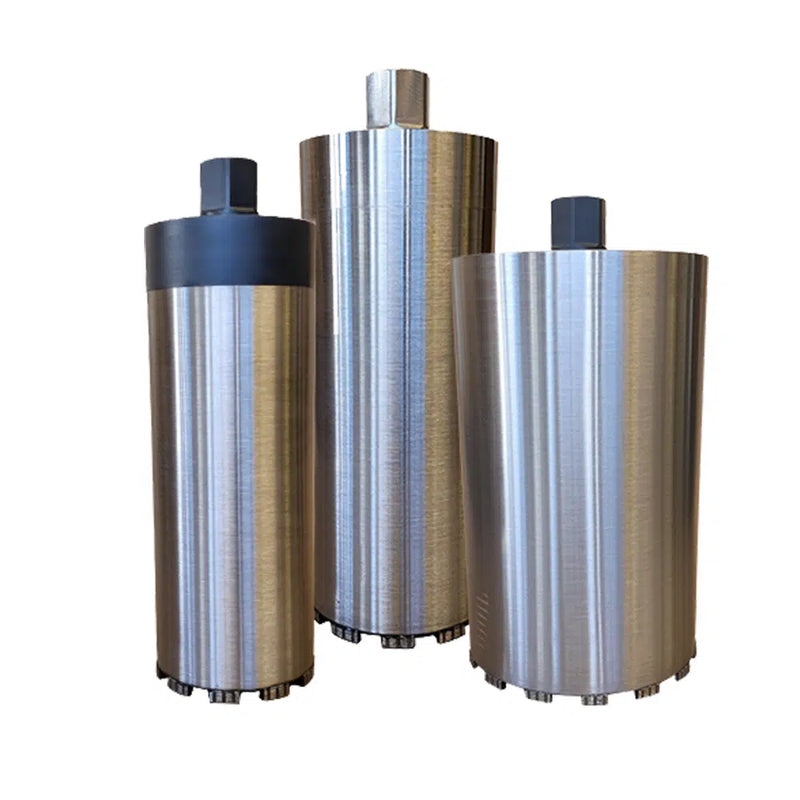 Three brushed steel core barrels standing upright on a white background in three diameters, each with a hex threaded connector at the top and a ring of segmented cutting crown at the base, the narrowest carrying a dark collar below its connector